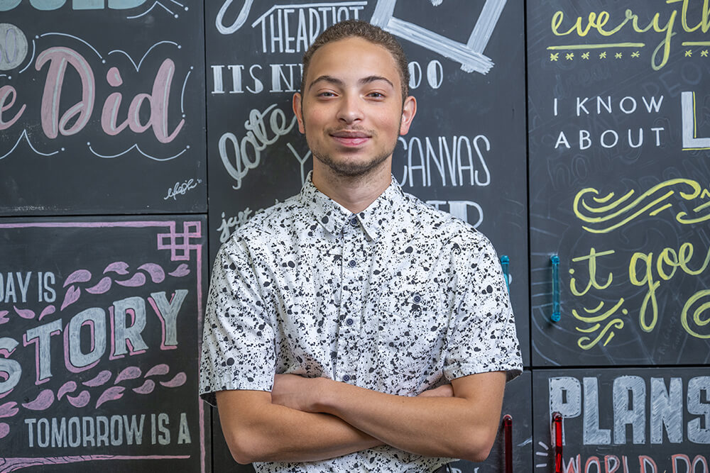 Graphic Design internship student in front of art wall