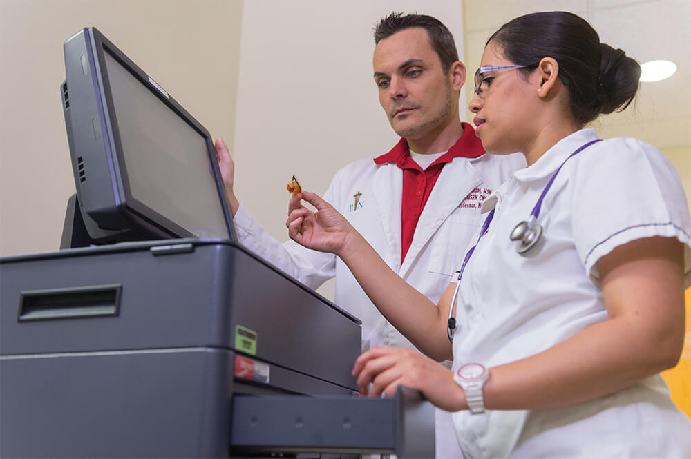 Nurse and nurses assistant reviewing results in front of computer