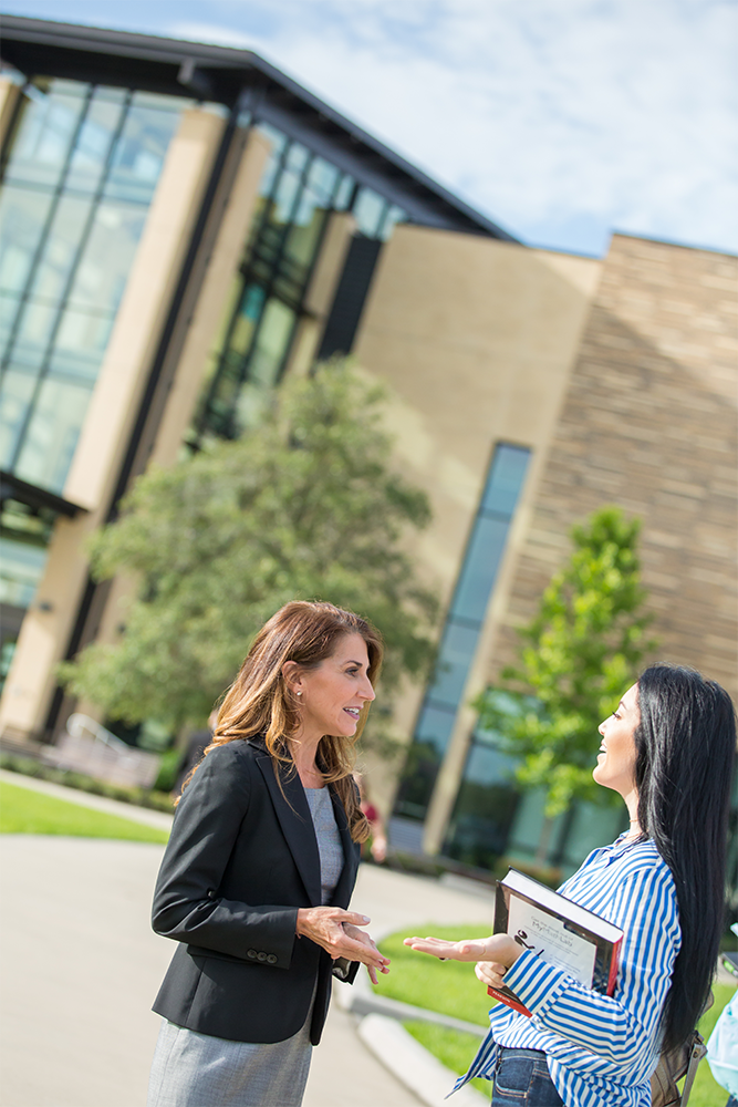 Two women talking outside of campus building